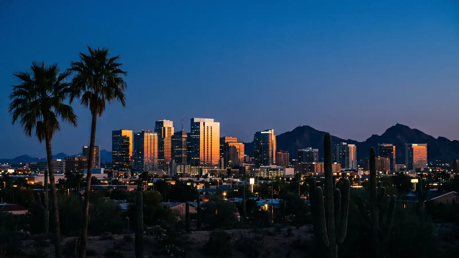 The downtown Phoenix skyline at blue hour with desert mountains on the horizon